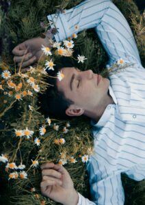 A person resting peacefully in a field of chamomile flowers.