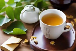 A white ceramic cup filled with Ginkgo Biloba tea on a wooden table, with a single Ginkgo leaf beside it