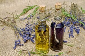 Two glass bottles of lavender essential oil with dried lavender sprigs on a burlap background.