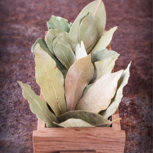  A wooden tray filled with dried bay leaves on a textured brown surface.