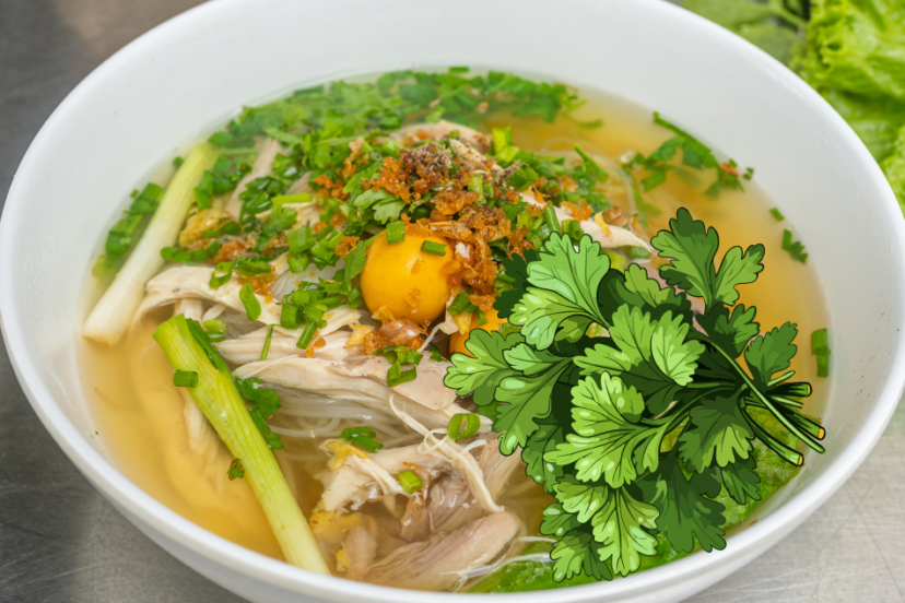 A bowl of chicken noodle soup garnished with fresh herbs, featuring a prominent coriander illustration on the side.