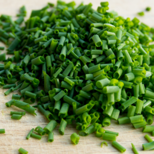  A close-up view of a pile of freshly chopped green chives on a wooden cutting board.