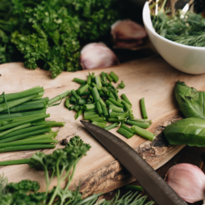  A close-up view of a bunch of fresh green chives tied together with a small pile of chopped chives on a wooden surface.