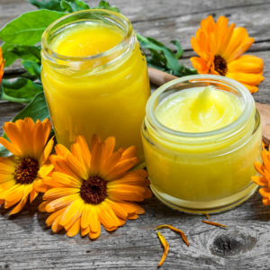  Jars of calendula salve with fresh calendula flowers.